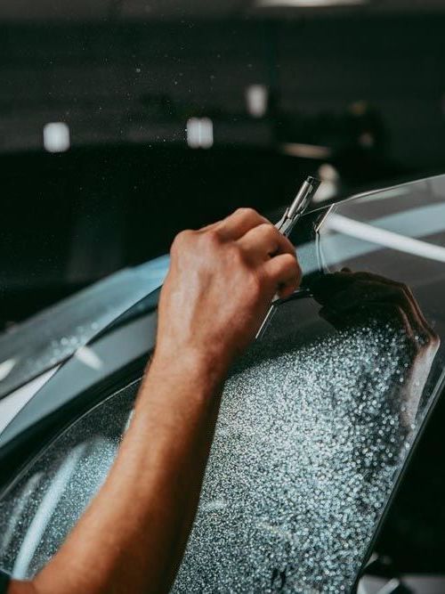 A person is applying tinted glass to a car window