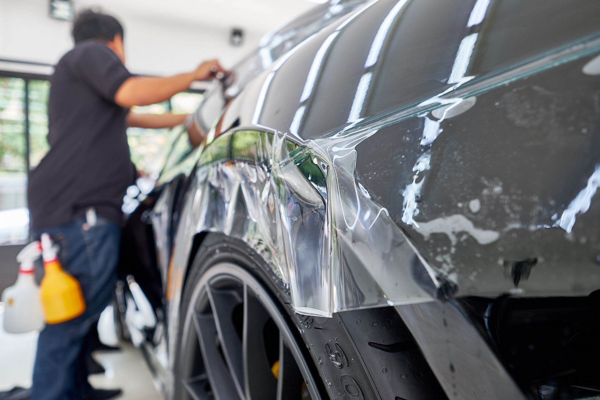 A man is wrapping a car with a protective film.