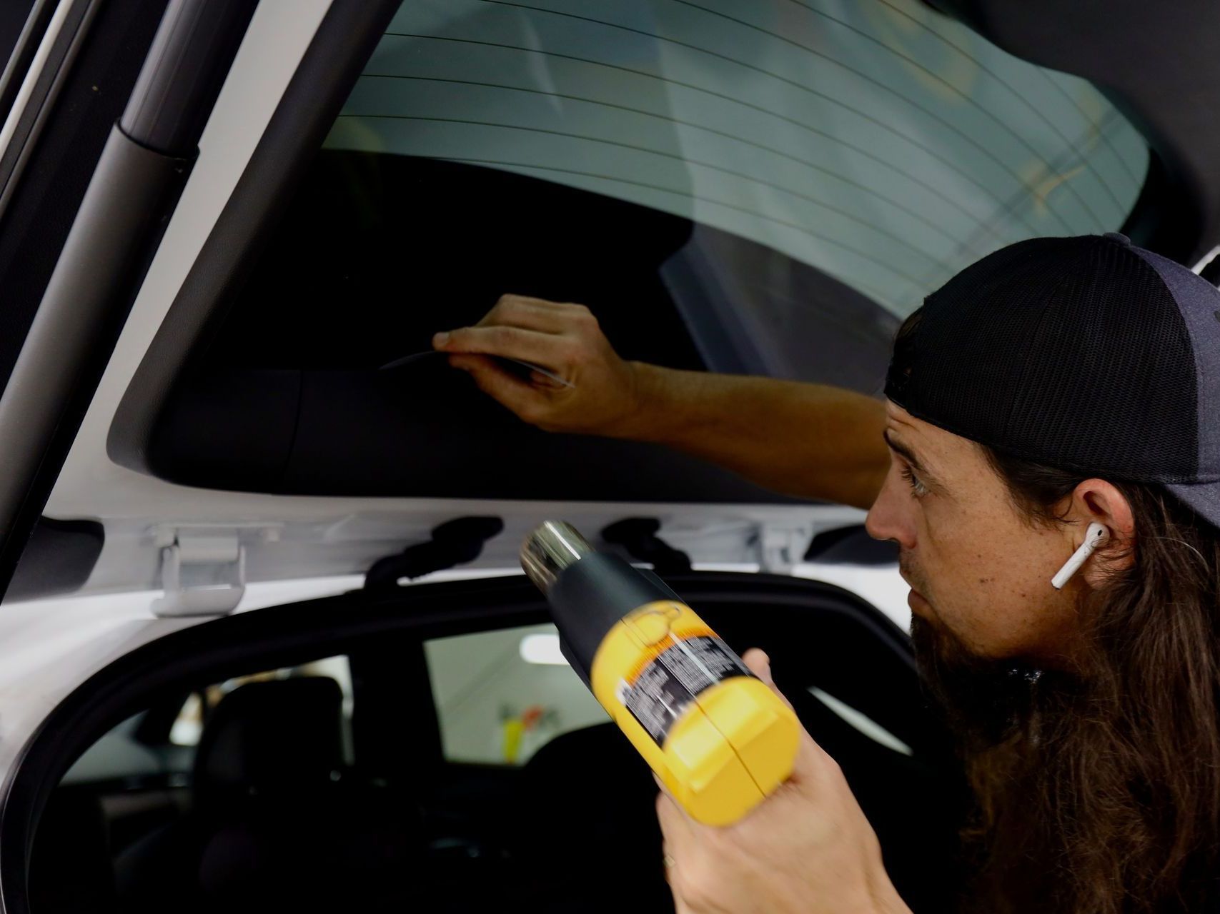 A man is applying tinted glass to a car window.